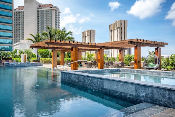 A rooftop pool with a pergola, outdoor seating, and a hanging chair.