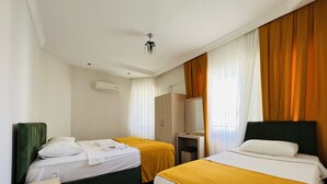 Een hotelkamer met twee bedden, een garderobe, een spiegel en een plafondventilator.