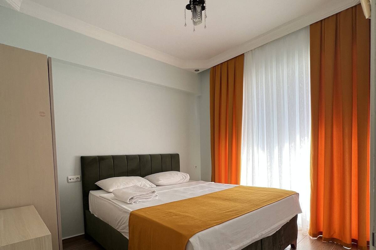 A bedroom with a bed, curtains, and a ceiling fan.