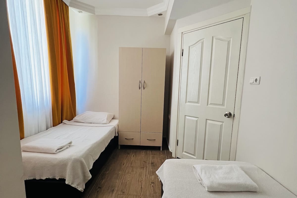 A room with two beds, a wardrobe, and a door.