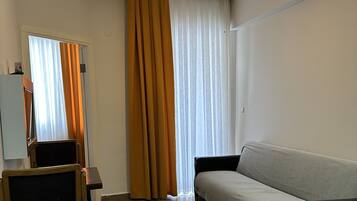 Una habitación con sofá, una silla de madera, una mesa y una lámpara en el techo.
