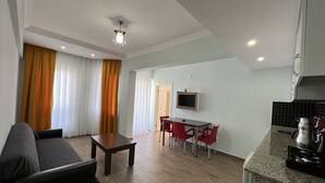 Een moderne woonkamer met een bank, een salontafel en een aan de muur bevestigde televisie.
