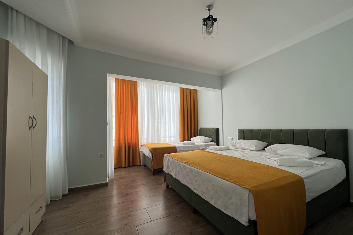 A hotel room with two beds, a wardrobe, and a ceiling fan.