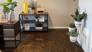 A room with a dark wooden floor, a round mirror on the wall, a small wooden console table with decorative items, and potted plants. - [SU 922-3] Campus-close 2 bedroom luxury (Norman)