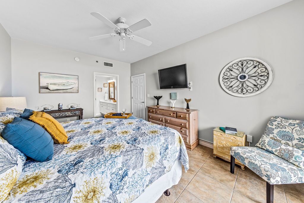 A bedroom with a bed, a chair, a TV, and a decorative wall piece.