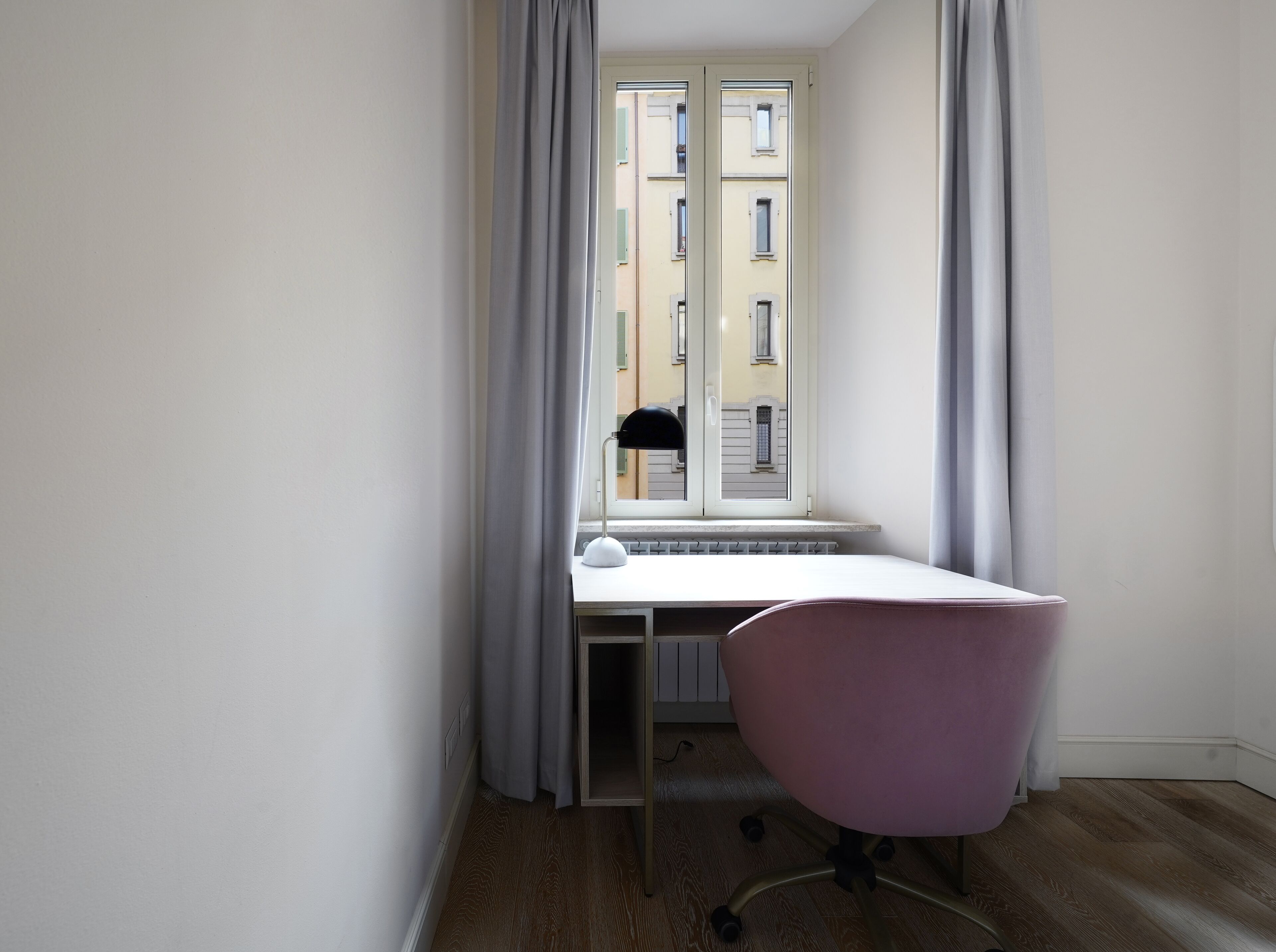 A small room with a window, a desk, and a chair.