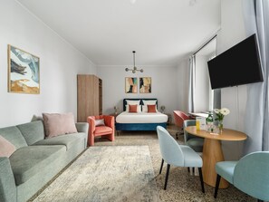 Een moderne hotelkamer met een bed, een bank, een stoel, een kleine tafel en een televisie.