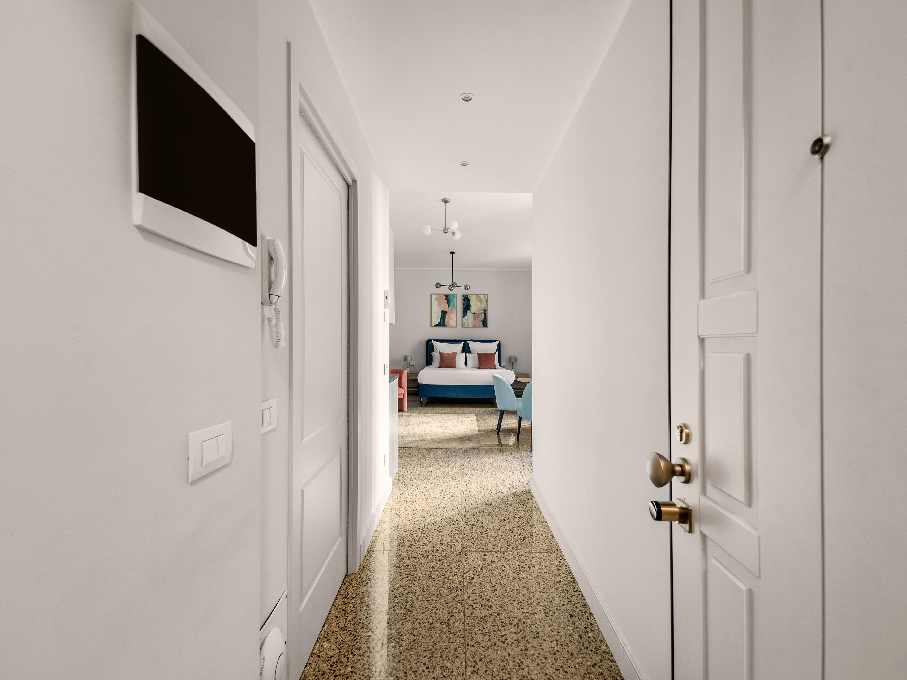 A hallway with white walls, a door with a brass handle, and a carpeted floor.