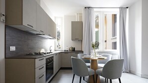 Een moderne keuken met een eethoek, met een centraal eiland, grijze stoelen en een raam met gordijnen.