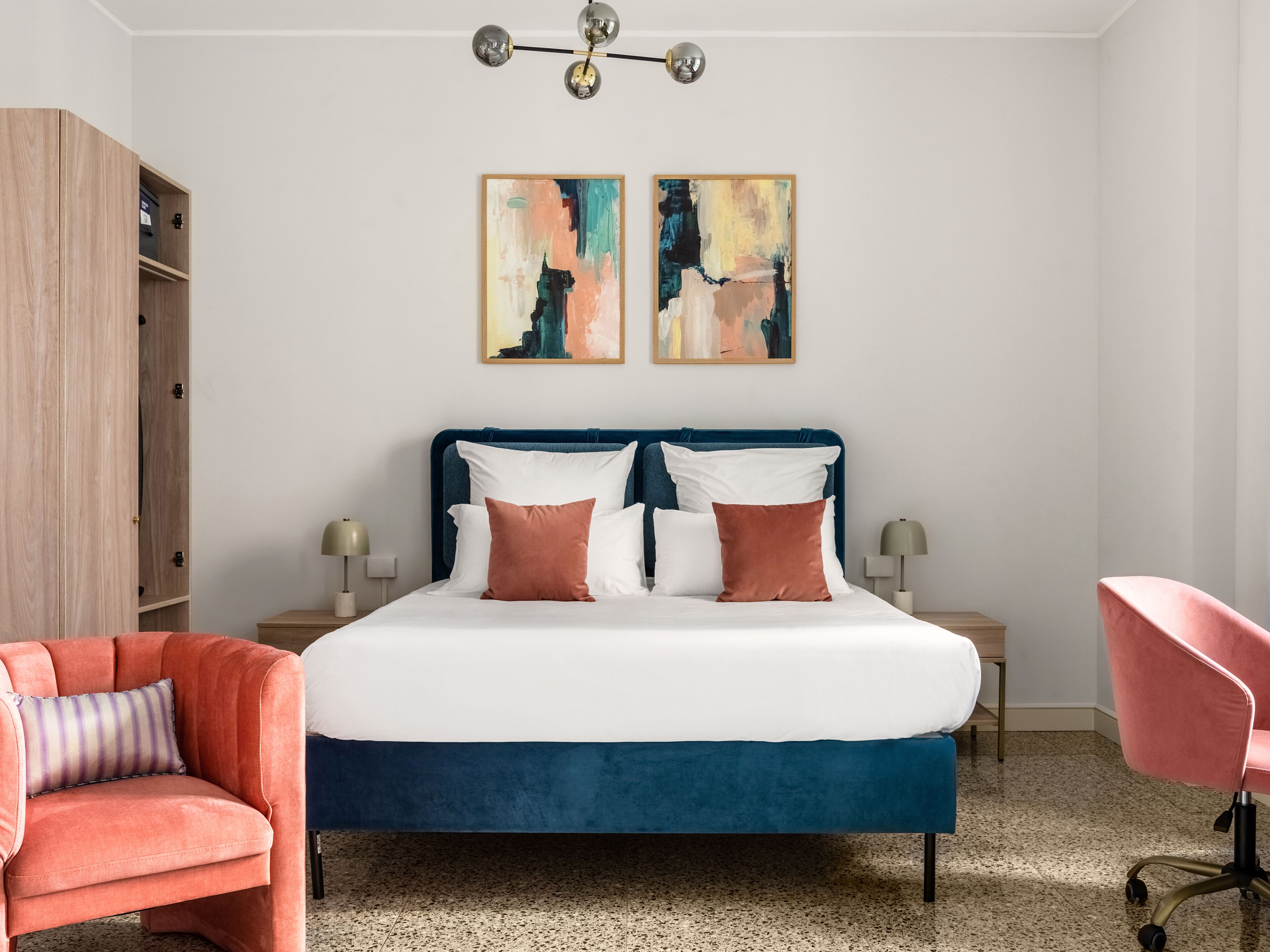 A modern bedroom with a large bed, two side tables, a wardrobe, and two chairs.