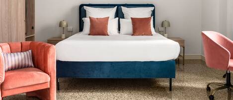 A modern bedroom with a large bed, two side tables, a wardrobe, and two chairs.