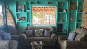 Ein wohnzimmer im Türkis-Ton mit gemusterten Sofas, einem Couchtisch und Dekoration auf Regalen.