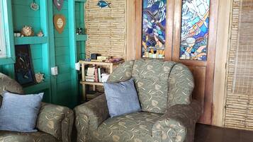 A cozy living room with two patterned sofas, a wooden coffee table, and a wall decorated with shells and a mosaic.