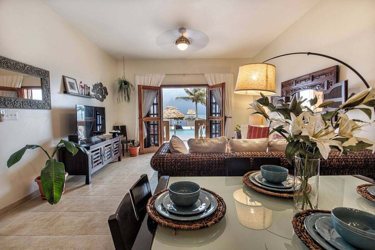 A spacious living area with a sofa, dining table, and a view of the sea.