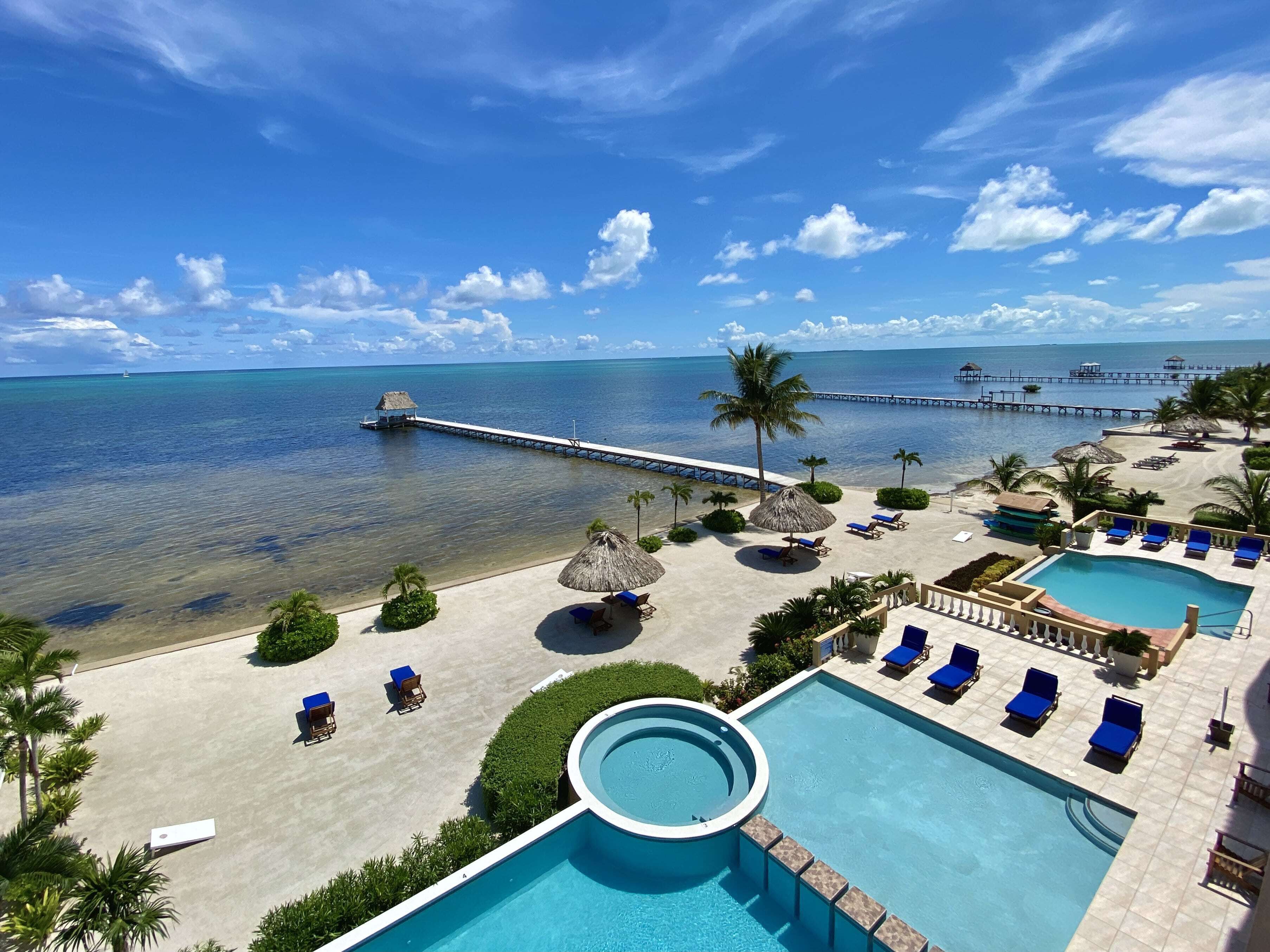 Un resort con piscina, sillas de descanso y un muelle que se adentra en el mar.
