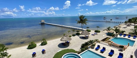 Un resort con piscina, sillas de descanso y un muelle que se adentra en el mar.