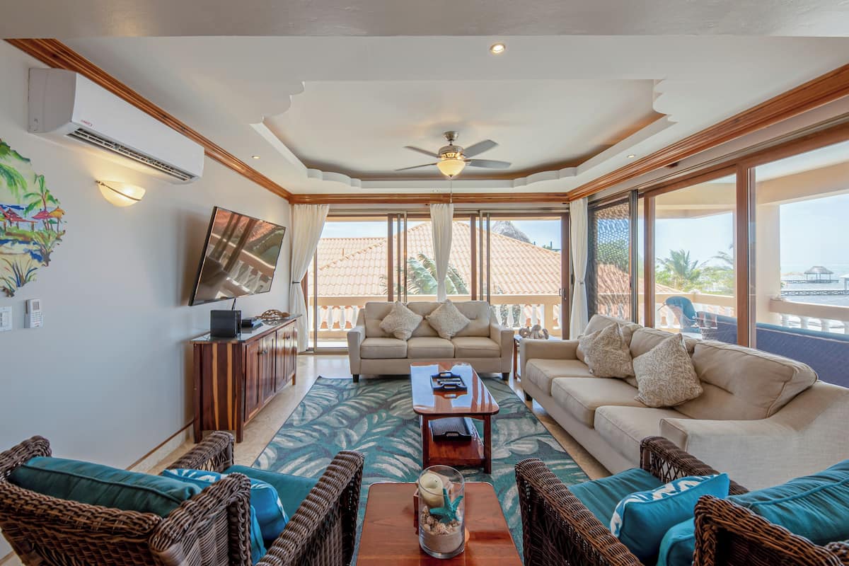A spacious living area with a ceiling fan, a flat-screen TV, and a sofa set.