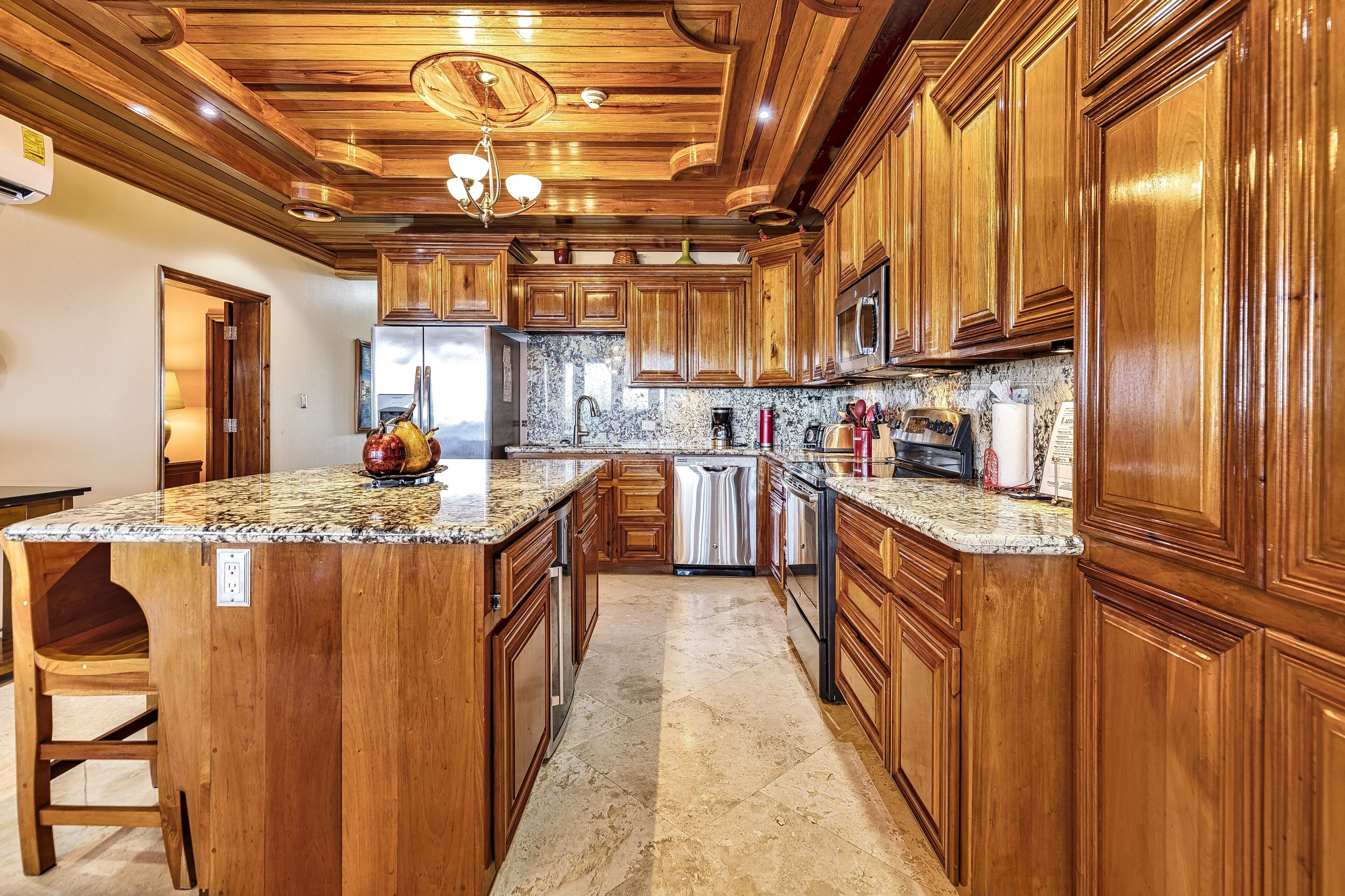 Una cocina con armarios de madera, encimeras de granito y una isla central.