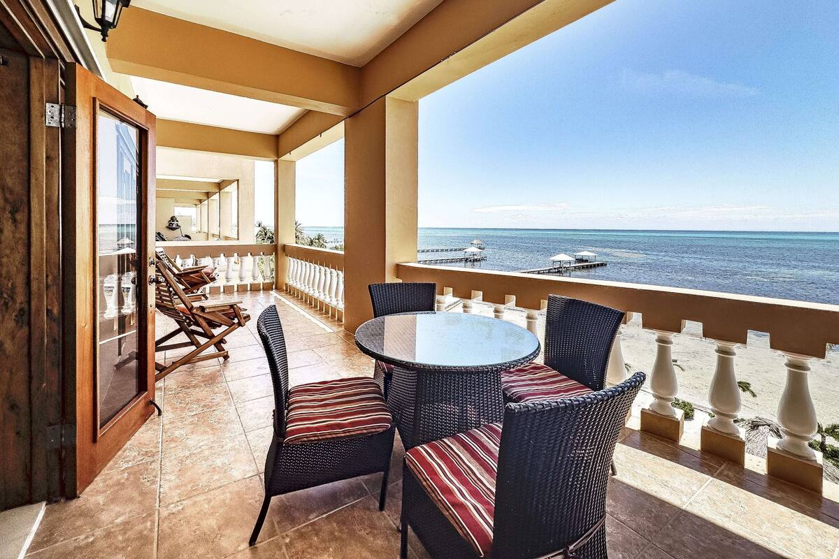 A balcony with wicker furniture, a glass door, and a view of the sea.