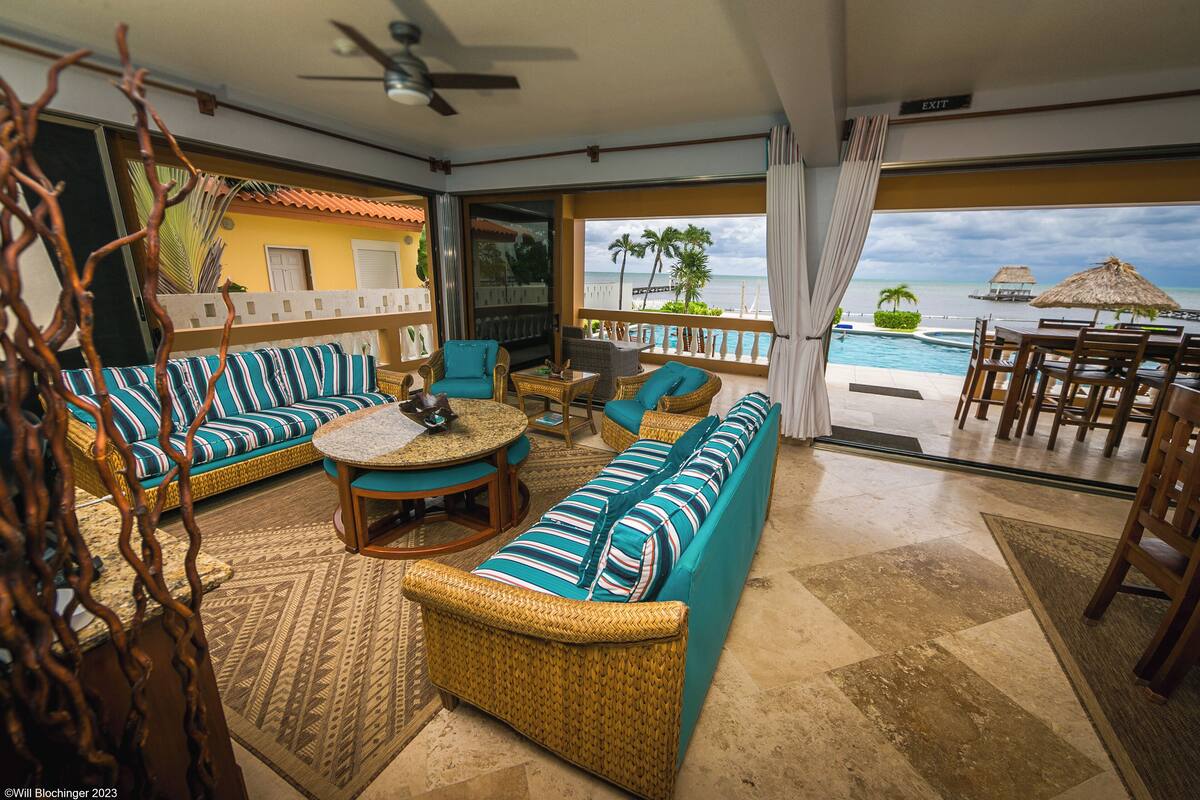 A spacious room with a large sofa, a round table, and a view of the ocean.