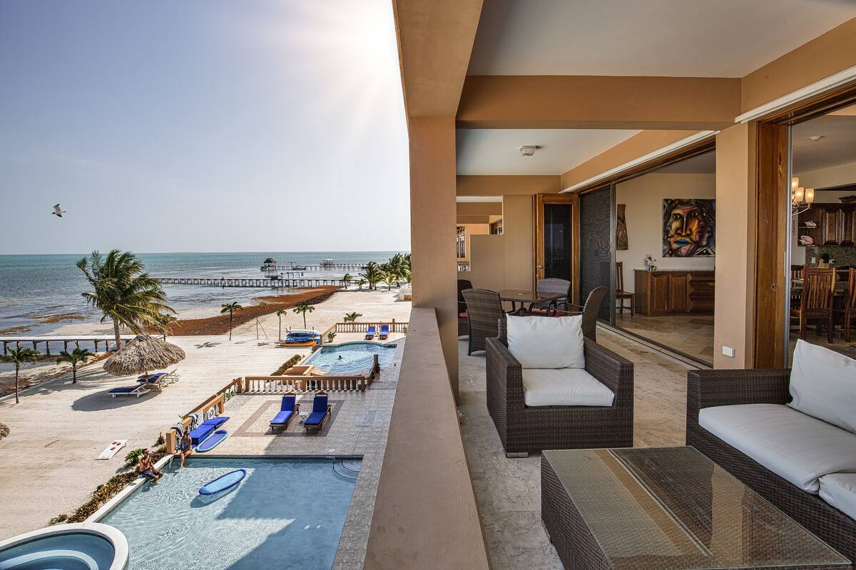 A pool area with lounge chairs, a small pool, and a view of the beach and ocean.