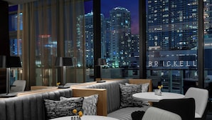 A modern hotel lobby with a city view, featuring a seating area with sofas and tables, large windows, and a visible sign reading "BRICKELL". - Element by Marriott Miami Brickell (Miami)