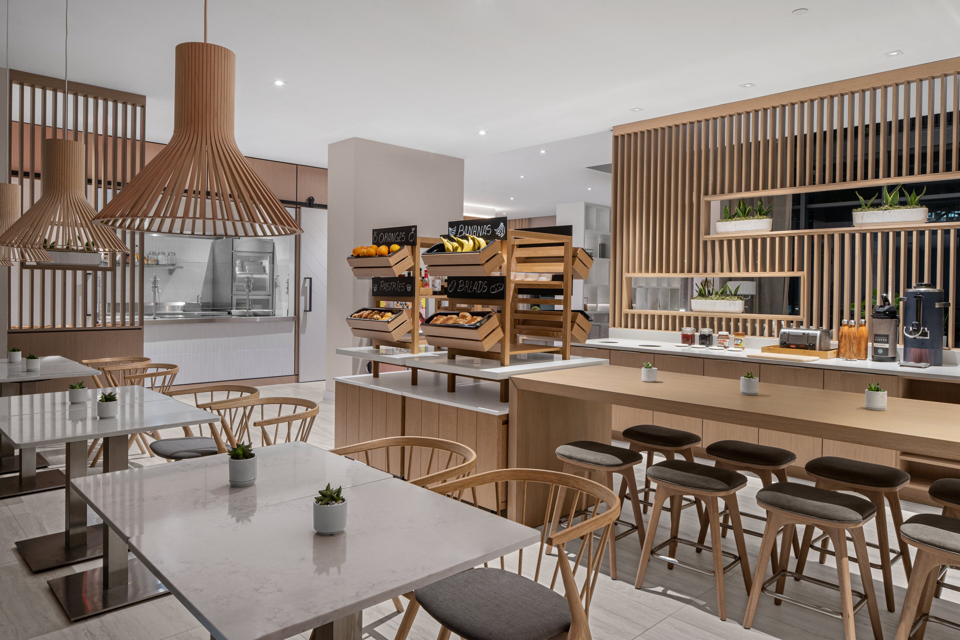 A modern kitchen with wooden accents, a central island with stools, and a breakfast bar.