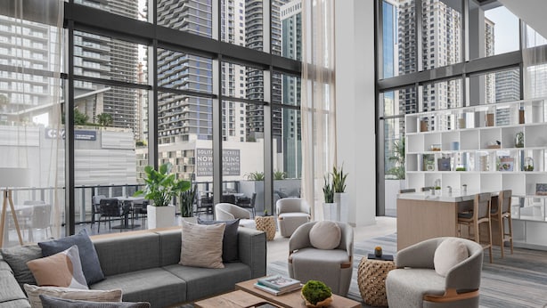 A modern living room with a grey sofa set, a coffee table, and a bookshelf. - Element by Marriott Miami Brickell (Miami)