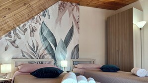 A hotel room with two beds, each with a headboard, a wall mural, a wooden ceiling, and a nightstand with a lamp.