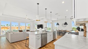 Una cocina moderna con una isla central, armarios blancos e iluminación colgante.