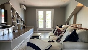 A modern living room with a sofa, a coffee table, and a built-in entertainment unit. - All-stop.  Rental Midships. (Annapolis)