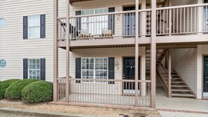 A multi-story building with a balcony on the second floor, a staircase on the right, and a small garden area. - Walk to Toomer's! Ground-Floor 4 BR Auburn Condo (Auburn)