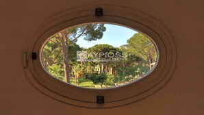 A circular window with a view of a garden and trees.