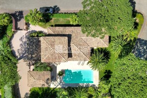 An aerial view of a property with a swimming pool, a patio area, and surrounding greenery. - Villa Pinede - heated pool (Grimaud)