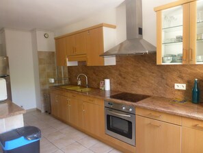Una cocina con armarios de madera, una campana extractora de acero inoxidable, un lavamanos doble y un horno empotrado.
