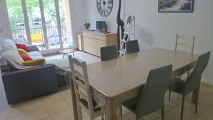 A dining area with a table and chairs, a sofa with cushions, a clock, a giraffe sculpture, and a painting on the wall. - Pleasant apartment 2 steps from downtown  (Port-Vendres)