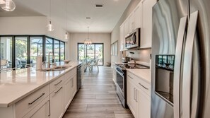 Una cocina moderna con una isla grande, electrodomésticos de acero inoxidable y vistas al exterior.