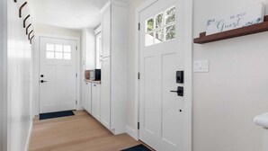 A hallway with white doors, a wooden floor, and a welcome sign on the wall. - Perch - Greenbank Cottage: quiet & view, relaxing outdoor oasis (Greenbank)