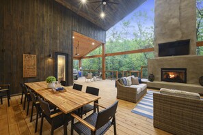 Une terrasse en bois avec une table et des chaises, une cheminée et un canapé.