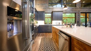 A modern kitchen with stainless steel appliances, wooden cabinets, and a large island. - New on Creek! HUGE Deck - Luxury Sleeps 15 - 4 Bedrooms (Broken Bow)