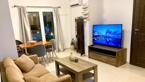 A living room with a sofa, coffee table, TV, dining table, chairs, and a decorative fish wall art.