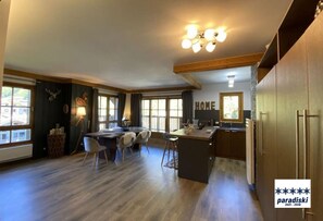 Une cuisine spacieuse avec un plancher en bois, un coin repas avec des chaises et un grand îlot central.
