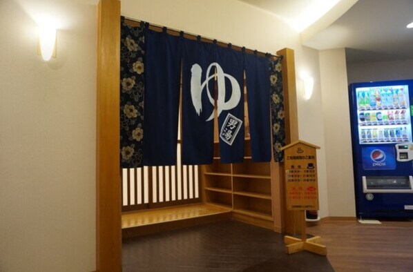 A corner room with a wooden bench, a vending machine, and a decorative sign.