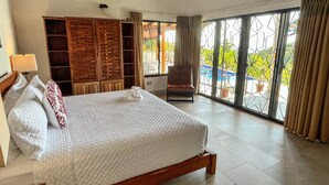 Een hotelkamer met een groot bed, een kledingkast, een stoel en een balkon met uitzicht op de omgeving.