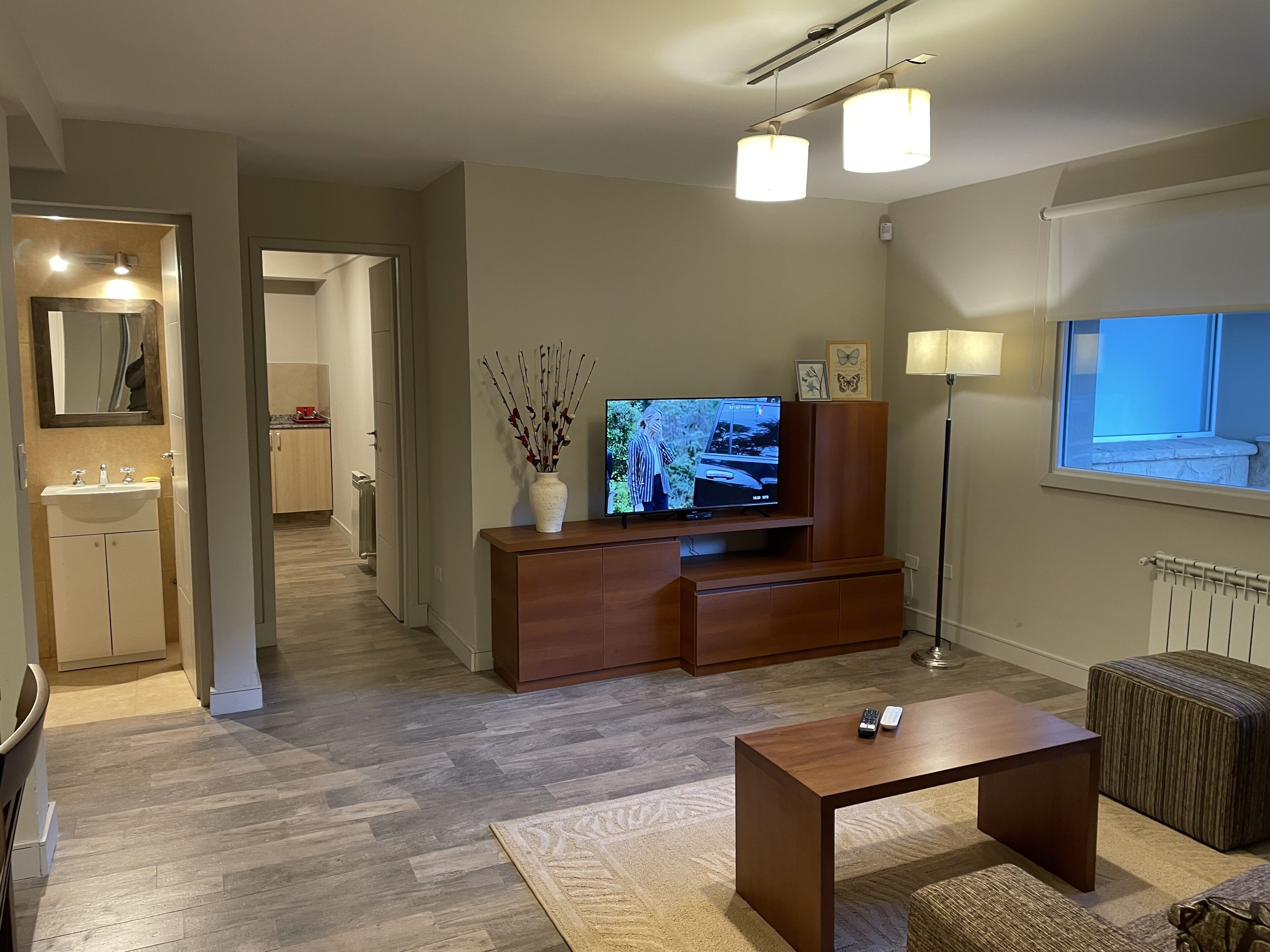 Una sala de estar moderna con televisor de pantalla plana, mueble de madera para entretenimiento y una mesita de centro.