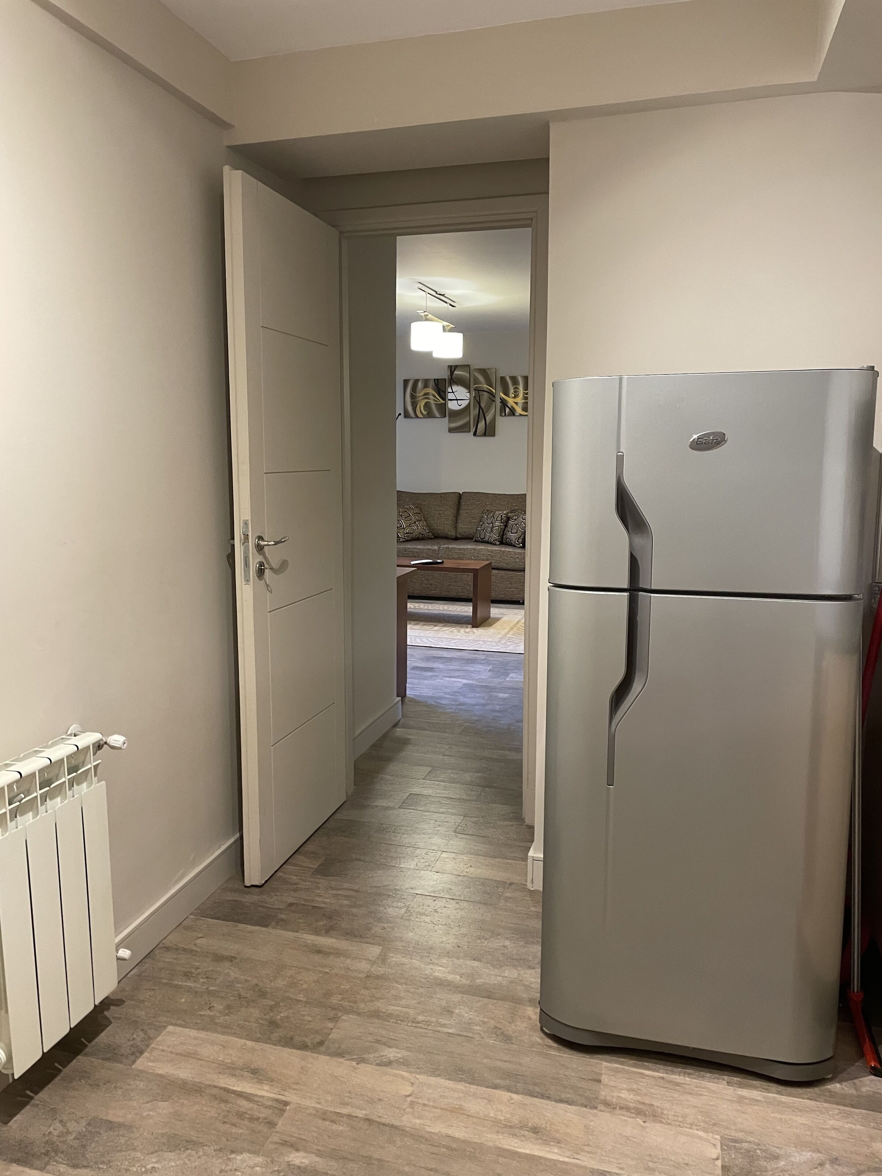 Un pasillo que conduce a una sala de estar con un refrigerador moderno y un radiador.