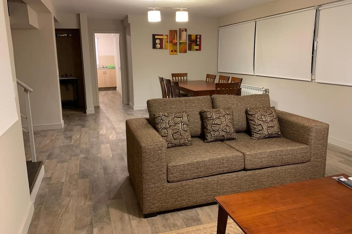 A living room with a sofa, coffee table, and a dining area with chairs and a table.