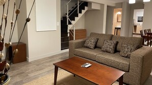 A modern living room with a sofa, coffee table, and a staircase leading to an upper floor.