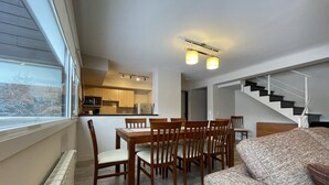 A compact living space with a dining area, kitchenette, and a staircase leading to another level.