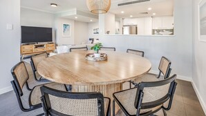 Un comedor moderno con una mesa redonda de madera, seis sillas y una lámpara colgante.